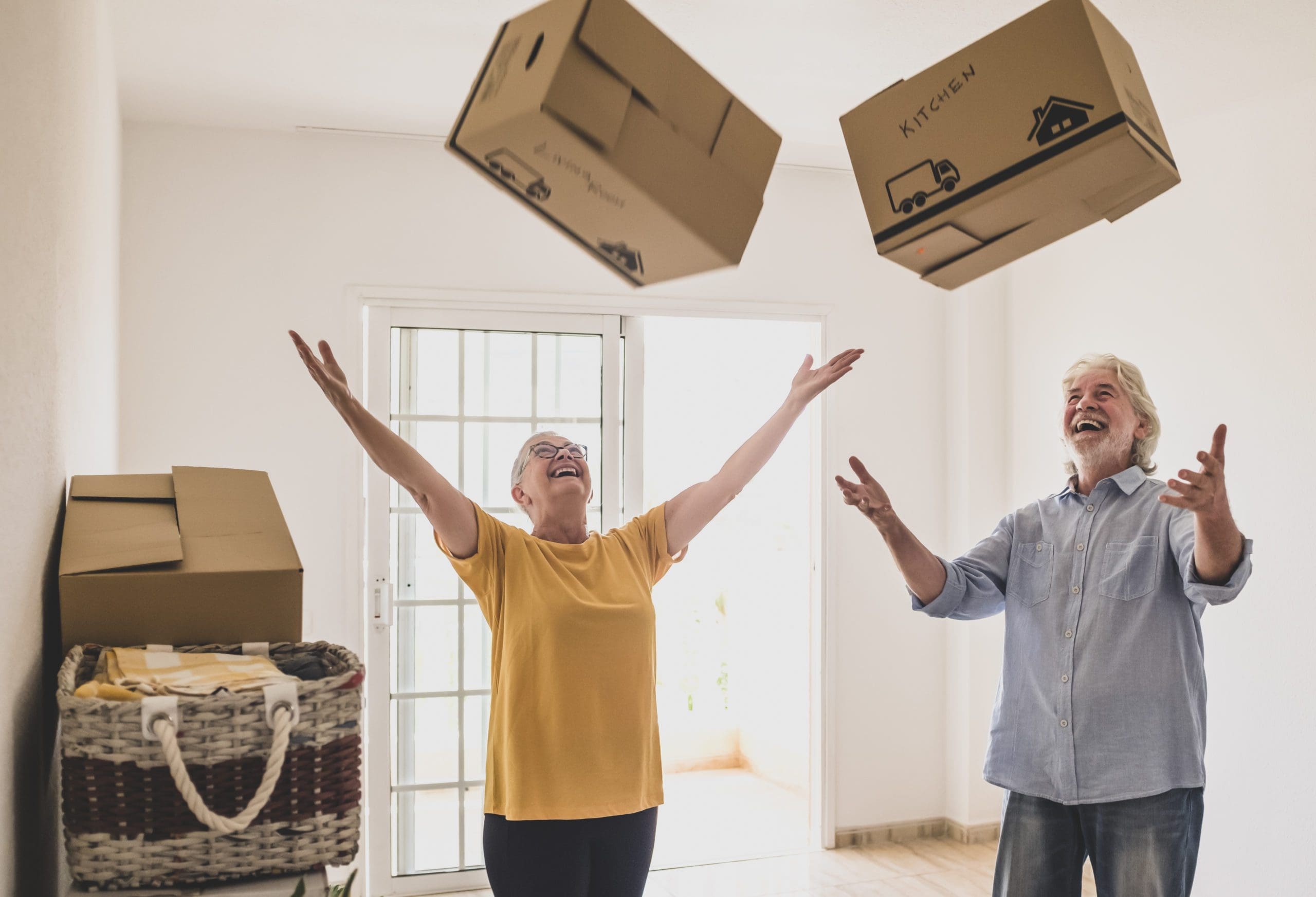 elderly couple throwing boxes in air
