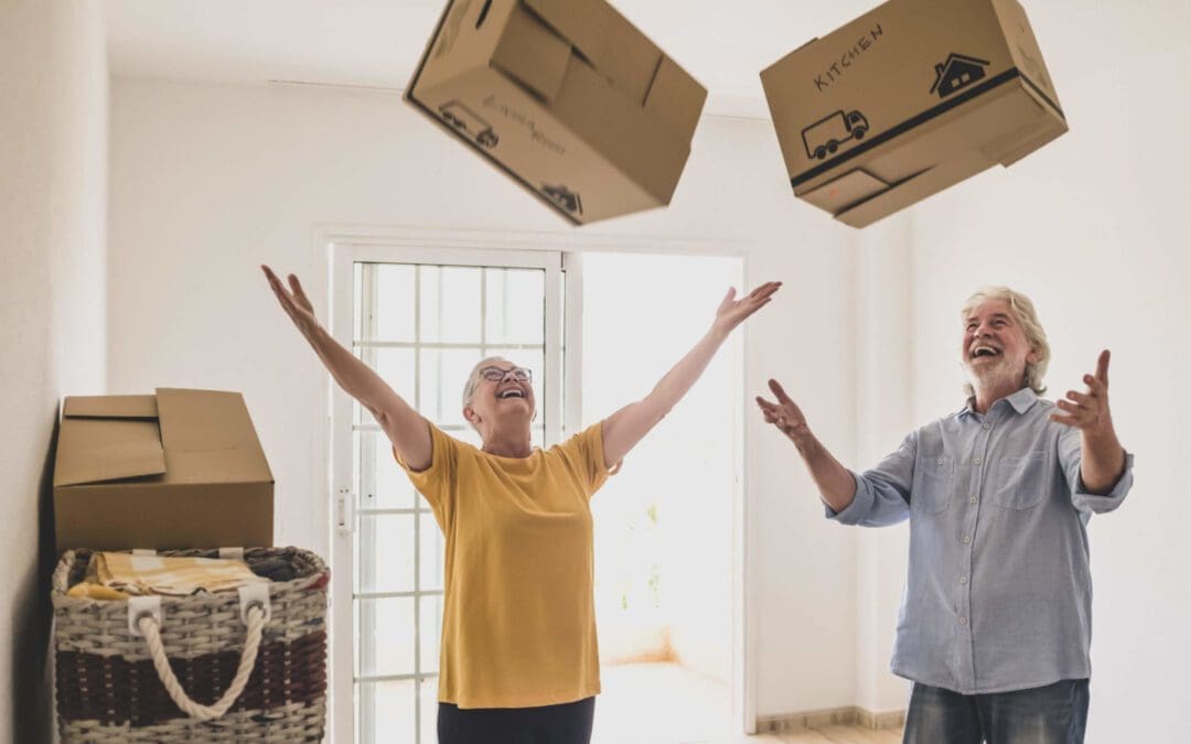 Senior couple celebrating moving home by throwing boxes in the air.